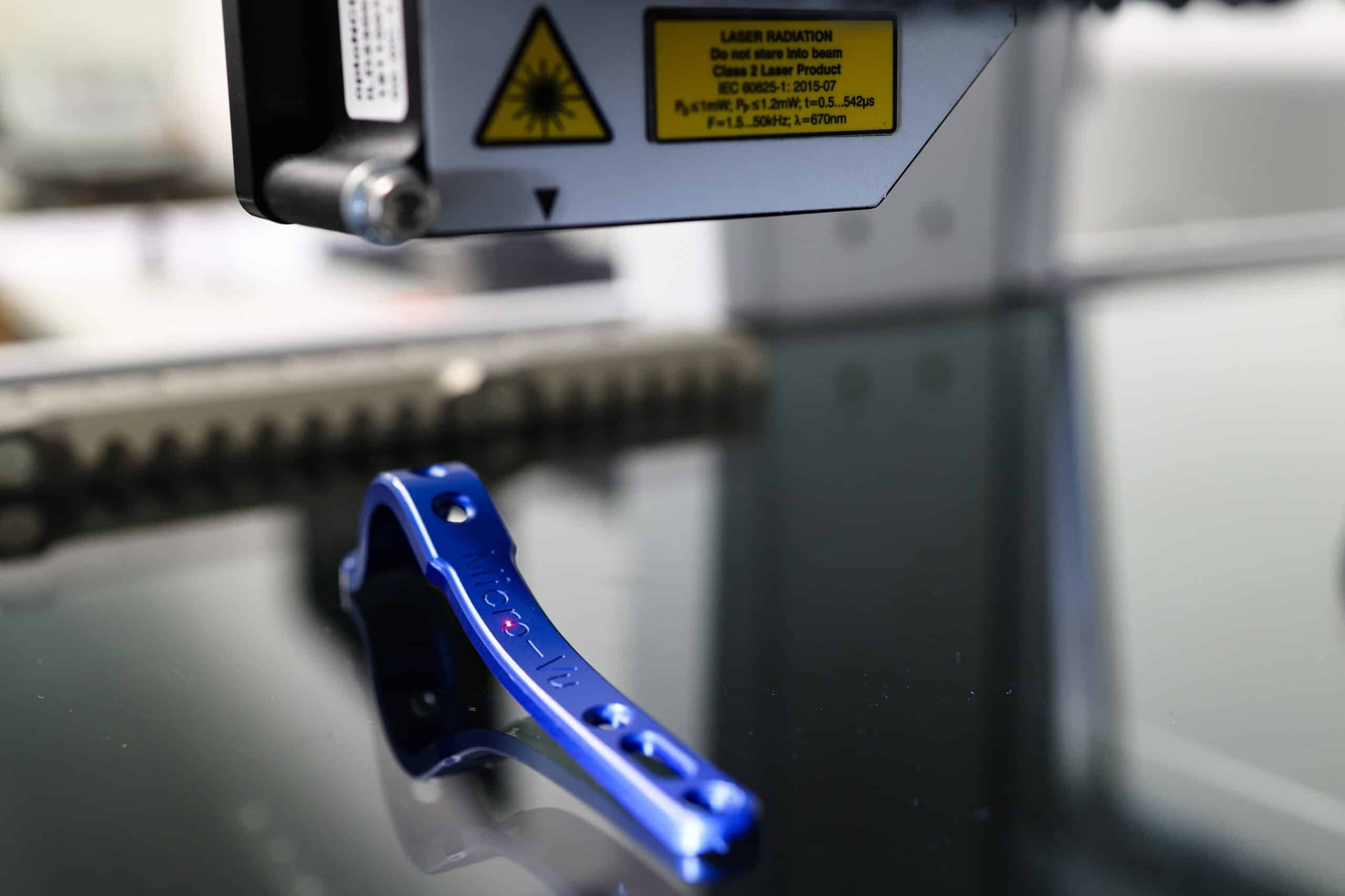 Sensor de distancia láser Micro-Vu midiendo pieza metálica sobre superficie de vidrio en sistema de metrología dimensional