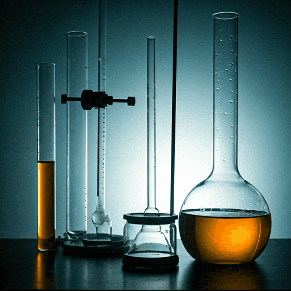 Vidría de laboratorio con líquidos amarillos: tubos de ensayo, probetas, matraz aforado y matraz Erlenmeyer sobre mesa oscura