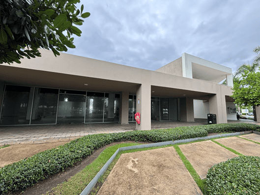 Sede corporativa moderna con fachada beige, ventanales de vidrio y jardín frontal